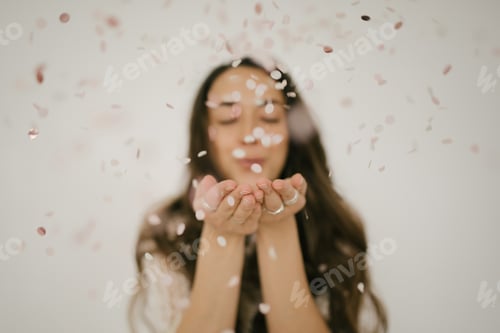 Preview: Woman blowing on confetti in her hands. Holiday celebrations