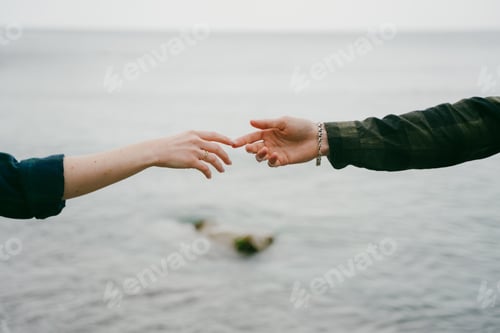 Preview: A couple stretches their arms to each other over the sea.