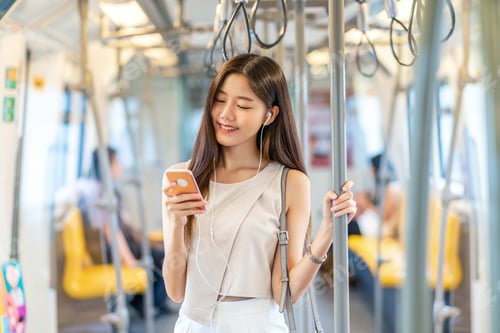 Preview: Young Asian woman passenger listening music via smart mobile phone in subway train