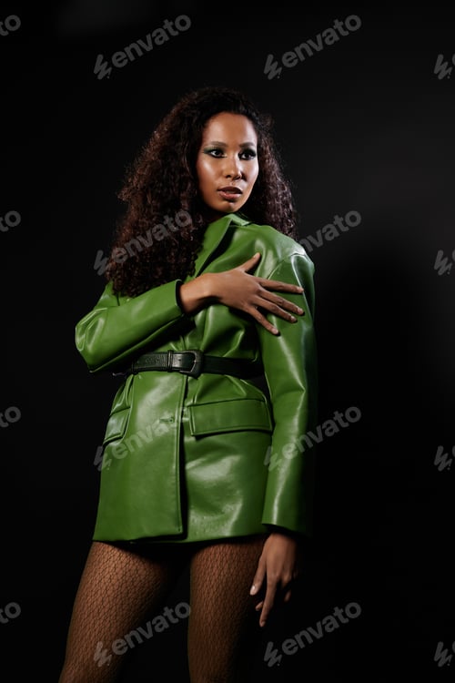 Preview: Striking elegance of a confident woman in a bold green outfit against a dark backdrop