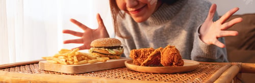 Preview: woman happy to eat hamburger, french fries and fried chicken on the table at home