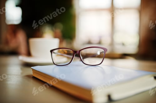 Preview: Glasses on Book with Coffee Cup in Background