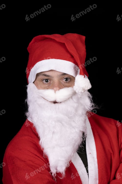 Preview: Young male with down syndrome posing in a Santa Claus costume isolated on a black background