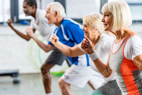 Preview: selective focus of senior sportswoman exercising with friends at gym