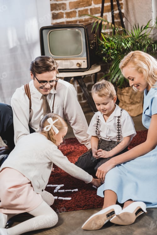 Preview: happy 50s style family playing dominoes together at home