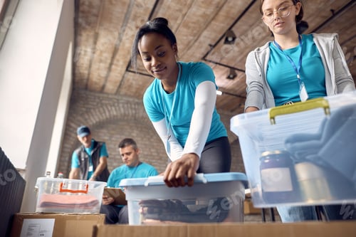 Preview: Below view of volunteers packing donation boxes for people in need.