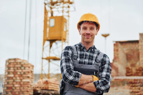 Preview: With arms crossed. Construction worker in uniform and safety equipment have job on building