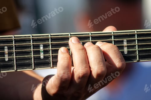 Preview: Closeup shot of a male hand playing guitar on blurred background