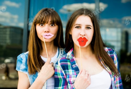 Preview: Portrait of two young women holding up lip costume masks