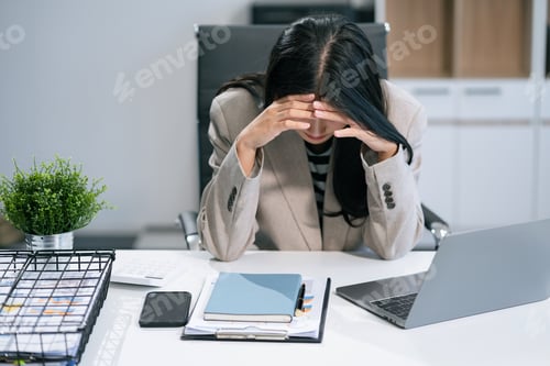 Preview: Young sad businesswoman is sitting at table, covering his face