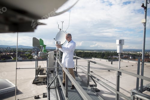 Preview: Male meteorologist updating meteorological equipment measurements at rooftop weather station