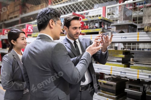 Preview: Business people checking machine parts in the factory