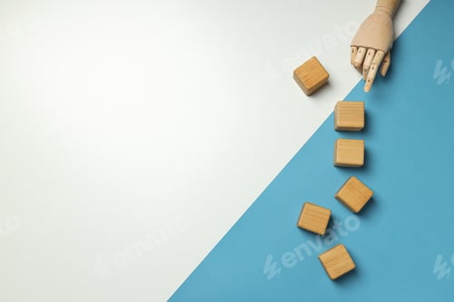 Preview: Wooden cubes and hand on white and blue background, space for text