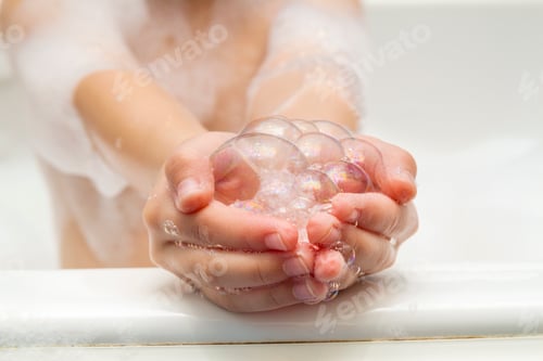 Preview: Childs little girls hands in bath with soap bubbles in it. Hygiene concept.