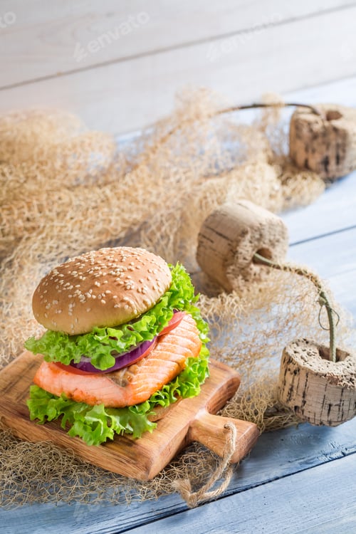 Preview: Tasty burger with fish and vegetables on old wooden table