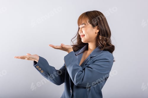 Preview: Asian happy portrait beautiful cute young woman smile standing presenting product holding something