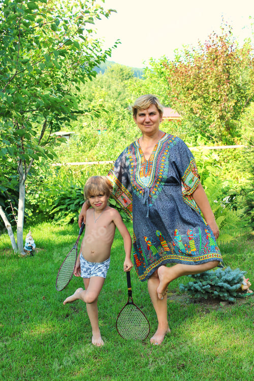 Preview: A 55-year-old active woman behaves like a child playing badminton with her grandson in the garden