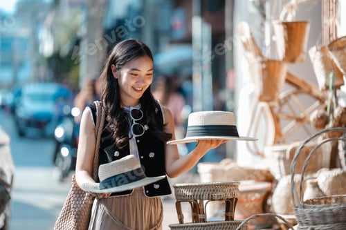 Preview: Tourist choosing handmade straw hats in a local market in Southeast Asia