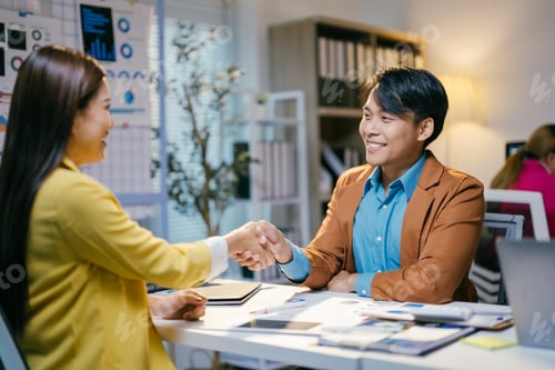 Preview: Two smiling business professionals shaking hands after successful meeting in modern office, concept