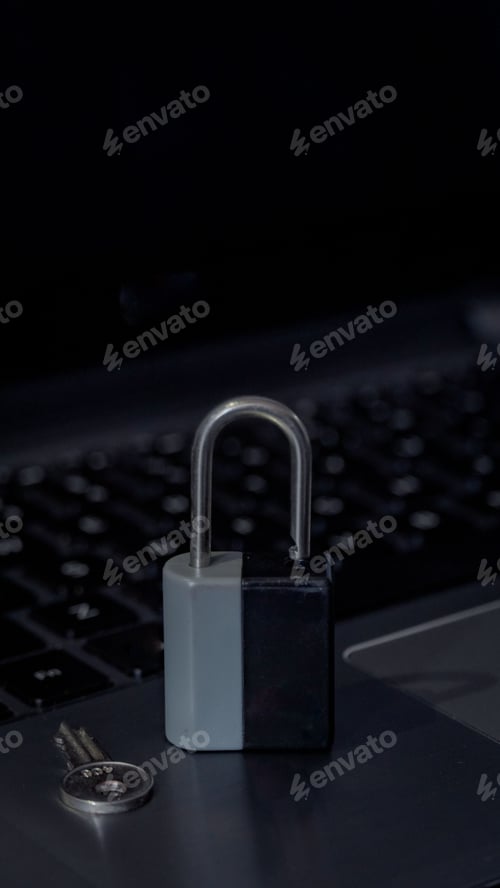Preview: Closeup shot of silver and black lock and key on laptop