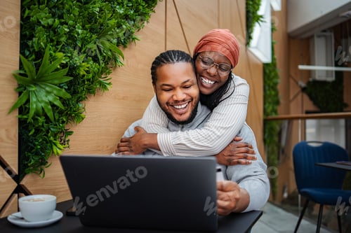 Preview: Happy couple embracing, doing online shopping using laptop