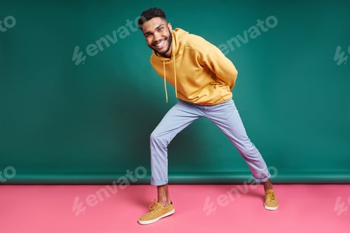 Preview: Happy African man looking at camera while standing against colorful background