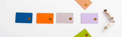 Preview: panoramic shot of colorful credit card templates and cash rolls on white