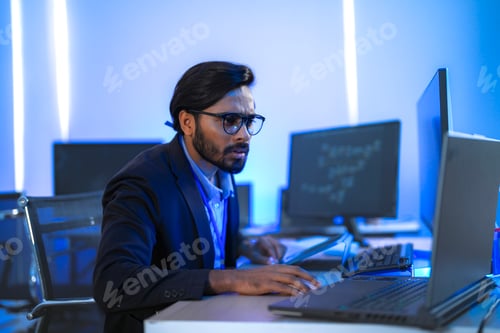 Preview: focused Indian financial analyst or software developer working late in a modern office