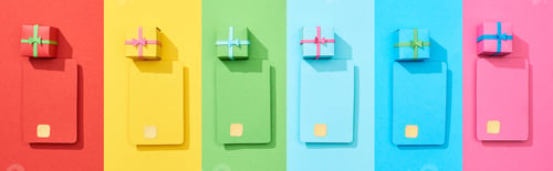 Preview: top view of multicolored empty credit cards and gift boxes on rainbow background, panoramic shot