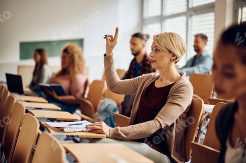 Preview: Mid adult student raising her hand to ask a question during a class at the university.