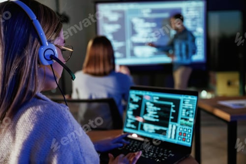 Preview: Audience is with laptops. Male business trainer is against projector with data, teaching people