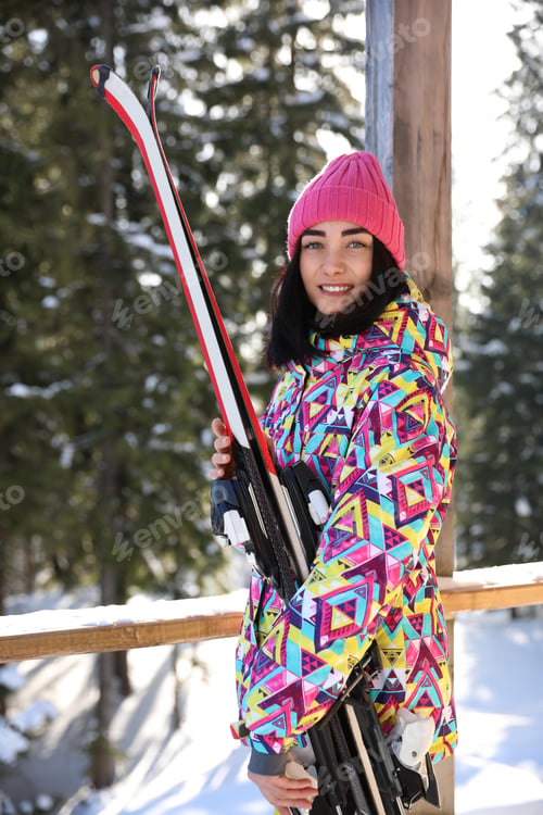 Preview: Young woman with ski wearing winter sport clothes in forest