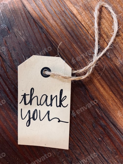 Preview: Old fashioned label paper with twine through it in cursive pen reads thank you, on wooden table