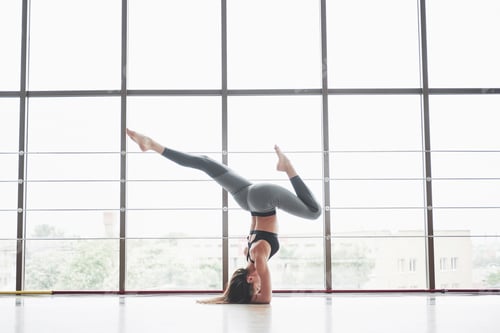 Preview: A sports sports woman who is doing yoga classes, stretching her legs near the big window