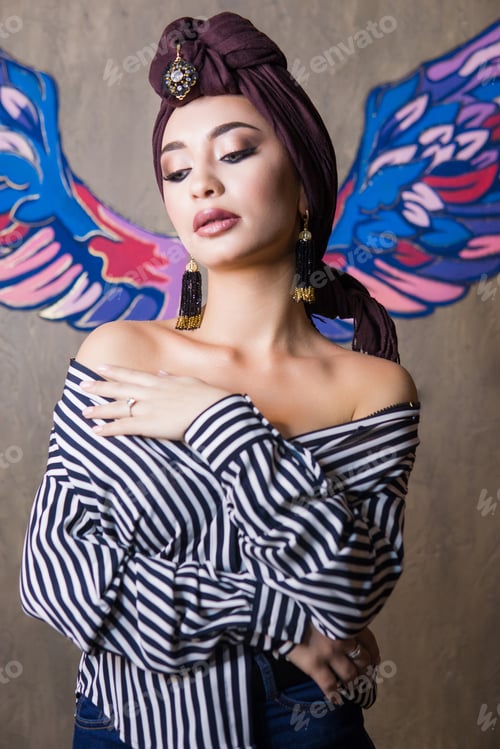 Preview: A woman of oriental appearance in a brown turban with bright makeup.