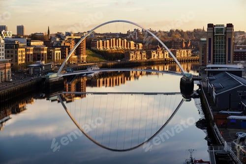Preview: Golden hour over a tranquil city river with a modern arch bridge