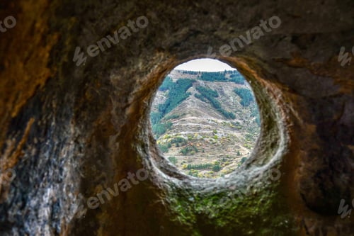 Preview: A round window in a sandstone cave with a view of the opposite mountain. Selective focus