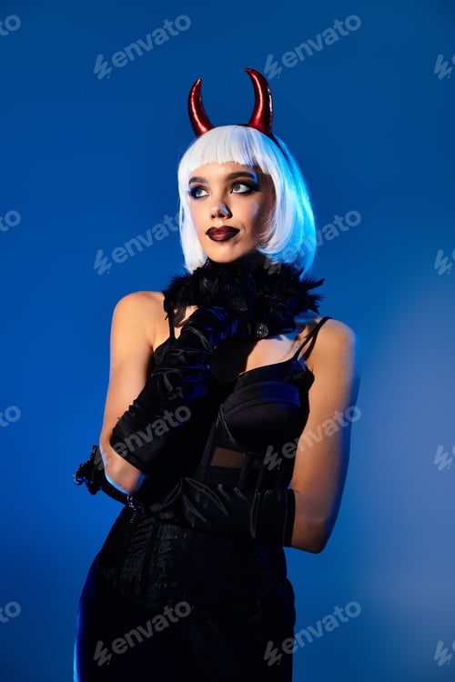 Preview: Young woman in enchanting Halloween costume poses dramatically against a vivid blue background
