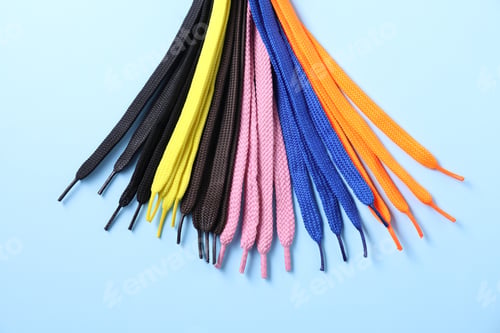 Preview: Many colorful shoe laces on light blue background, flat lay