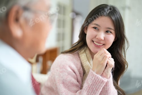 Preview: Smiling woman talks with older man in cozy indoor setting during daylight hours