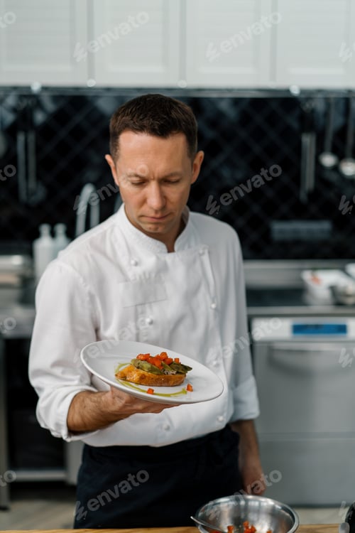 Preview: Professional satisfied chef showing freshly prepared toast with roasted avocado and tomatoes