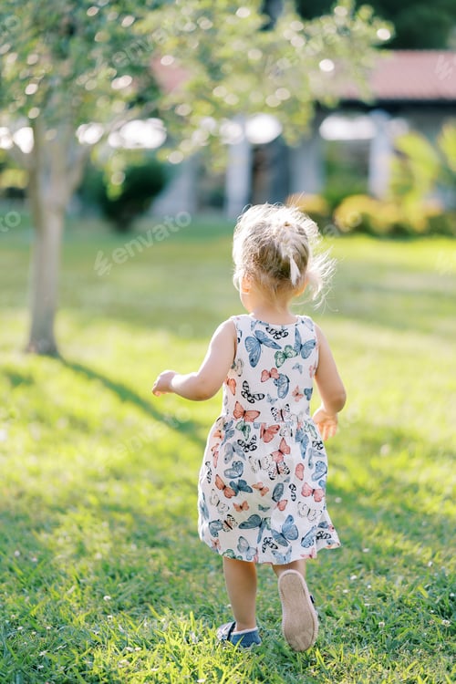 Preview: Little girl goes to a green tree in the garden. Back view