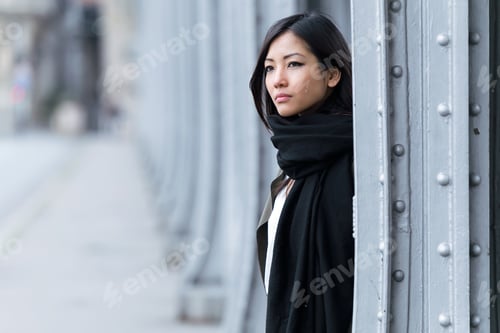 Preview: Pretty asian young woman looking sideways in the street.