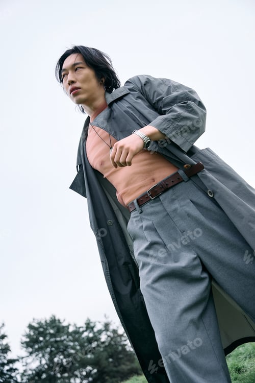Preview: Stylish young man in fashionable grey outfit enjoying a serene park stroll