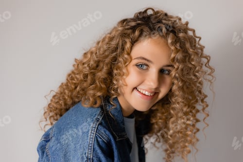 Preview: portrait of a charming smiling blonde girl with blue eyes and curly hair in a denim jacket