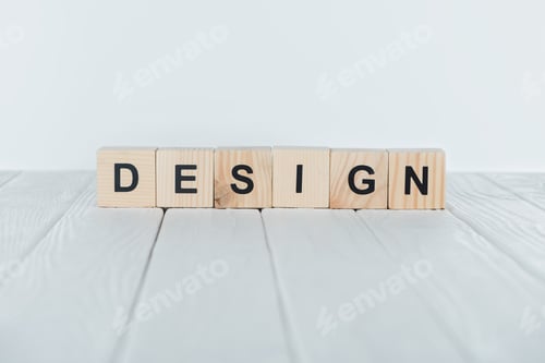 Preview: close up view of design word made of wooden cubes on white wooden tabletop