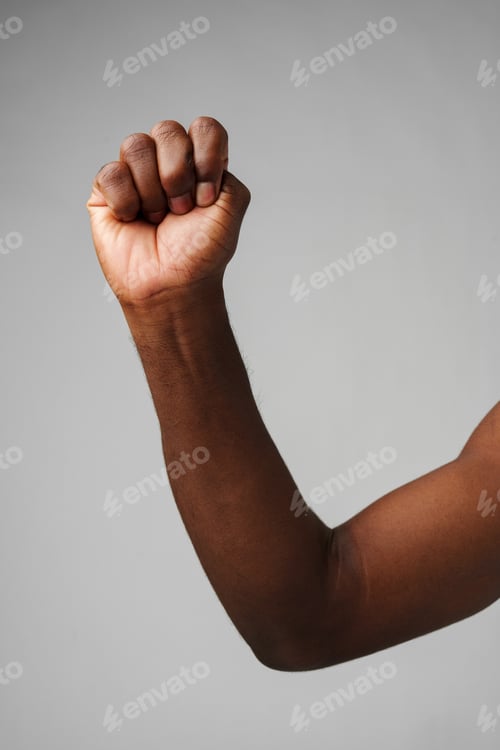 Preview: Raised Fist of Determination and Strength Against a Gray Background
