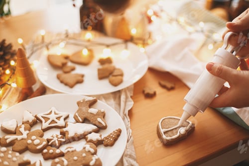 Preview: Decorating gingerbread cookies with icing on rustic table. Christmas holiday tradition and advent