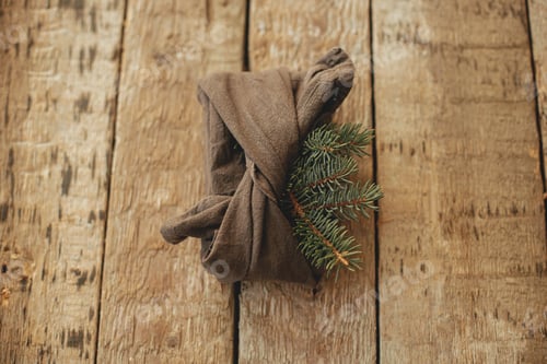 Preview: Stylish christmas gift wrapped in fabric with fir branch on rustic wooden table top view. Zero waste