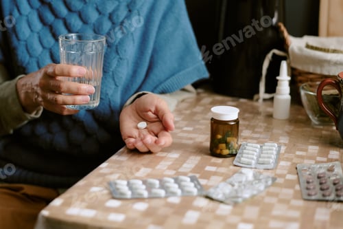 Preview: Senior Caucasian Woman Holding Pill and Glass of Water While Sitting Indoors